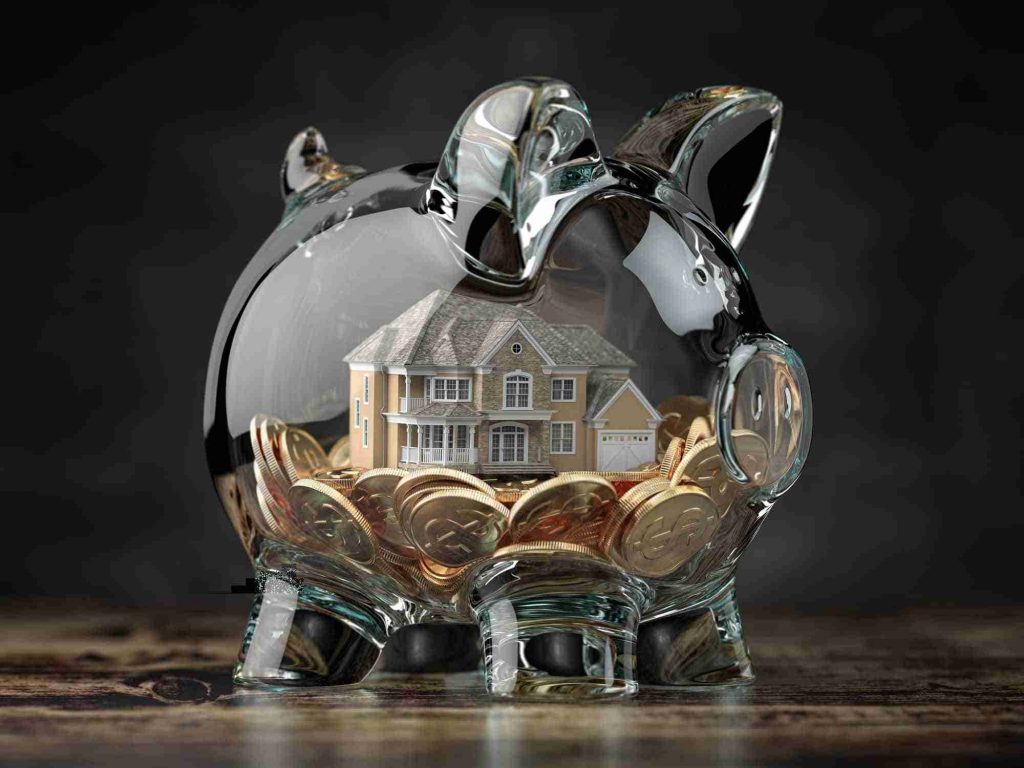 Glass piggy bank with coins and house. Mortgage, savings for real estate or to buy a house concept.