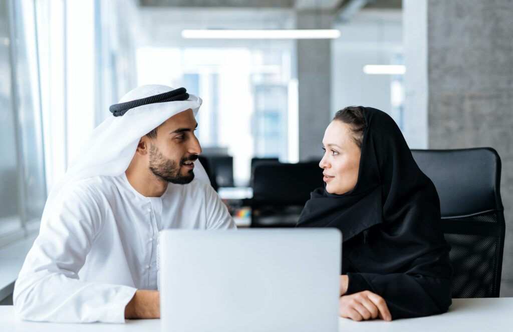 Handsome man and woman with traditional clothes working in an office of Dubai